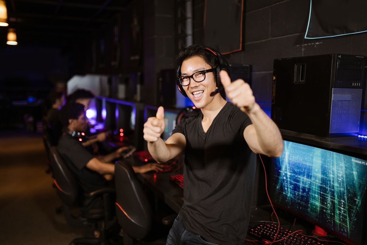 services-03 Happy gamer giving thumbs up in an esports gaming center with computers.